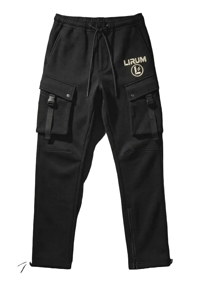 Black cargo pants with multiple utility pockets, a drawstring waist, and a white 'LIRUM' logo printed on the left hip, displayed flat against a dark wood plank background.